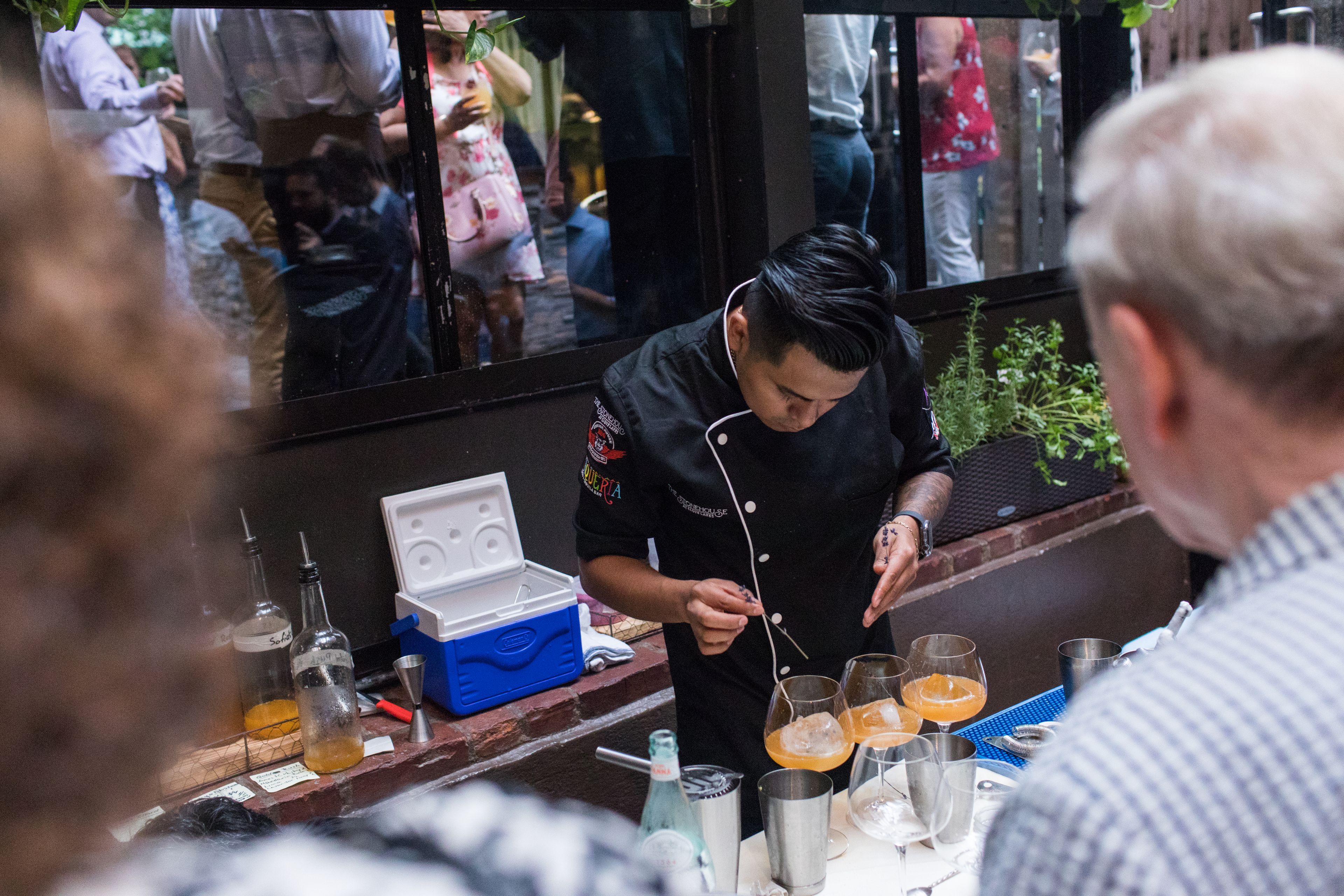 Man in black chef's coat prepares orange cocktails