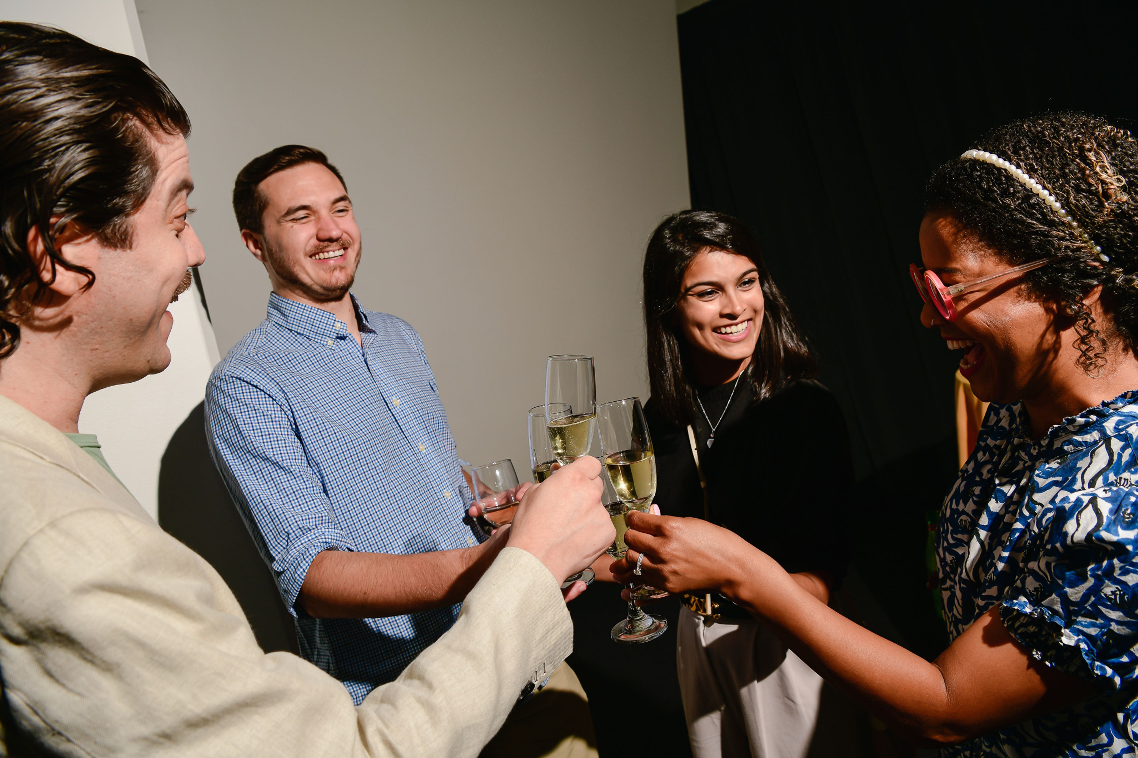 Four people clinking Champagne flutes