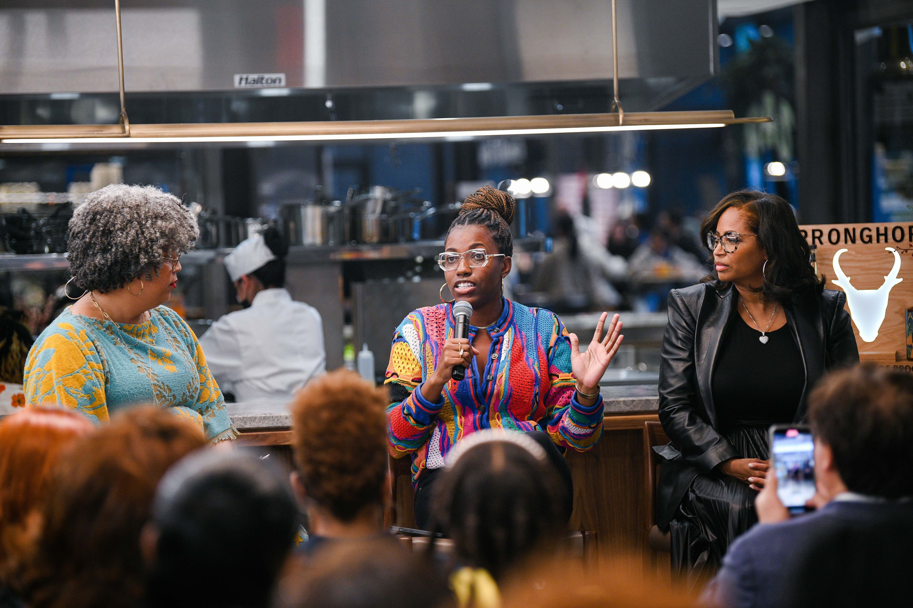 Three women sitting in high chairs on a panel