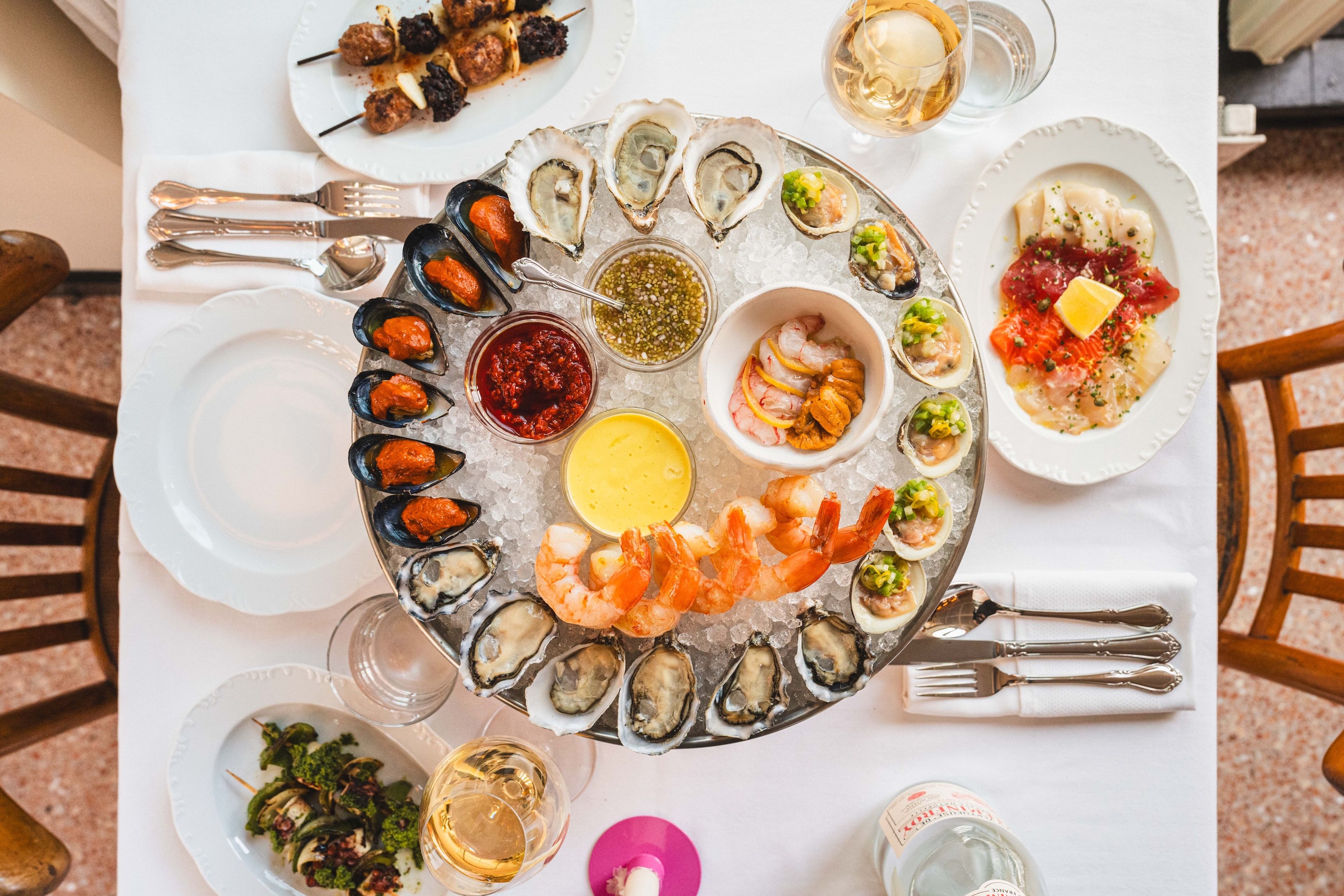 From-above shot of a raw bar platter and other dishes at a fancy dinner table