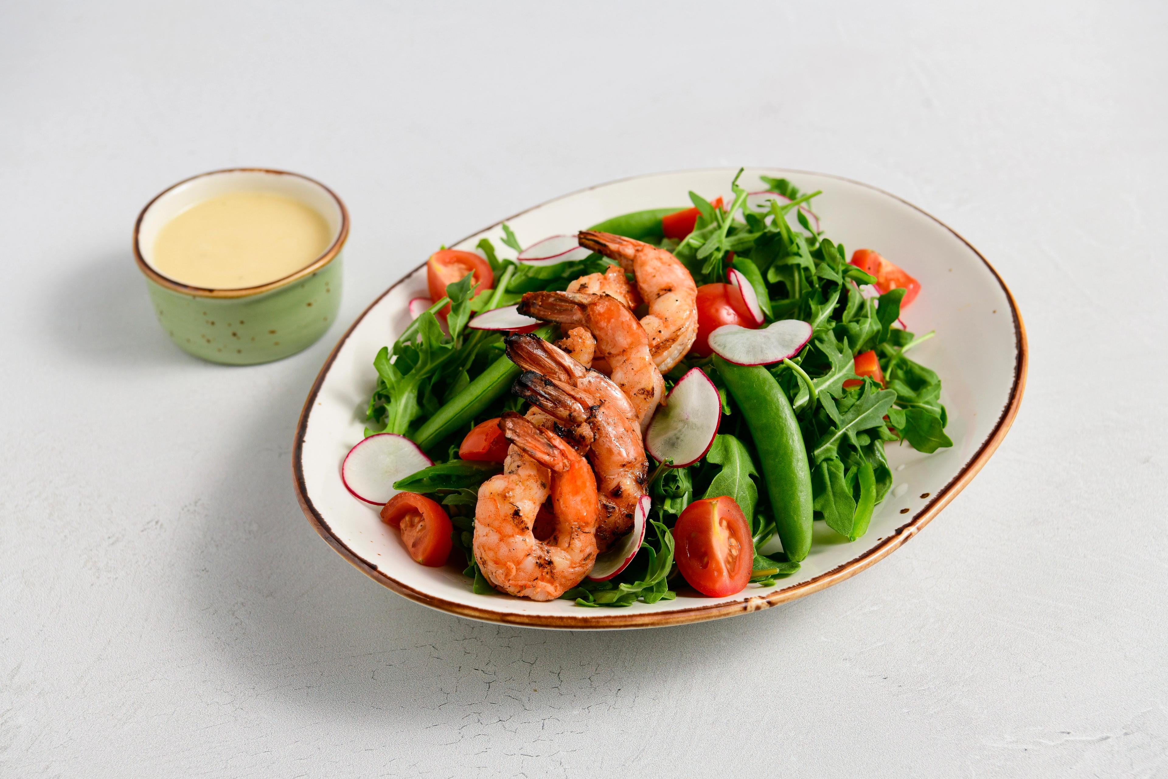 An arugula salad with Blackened Shrimp, Snap Pea, Cherry Tomatoes, Radishes, and Lemon Vinaigrette on the side