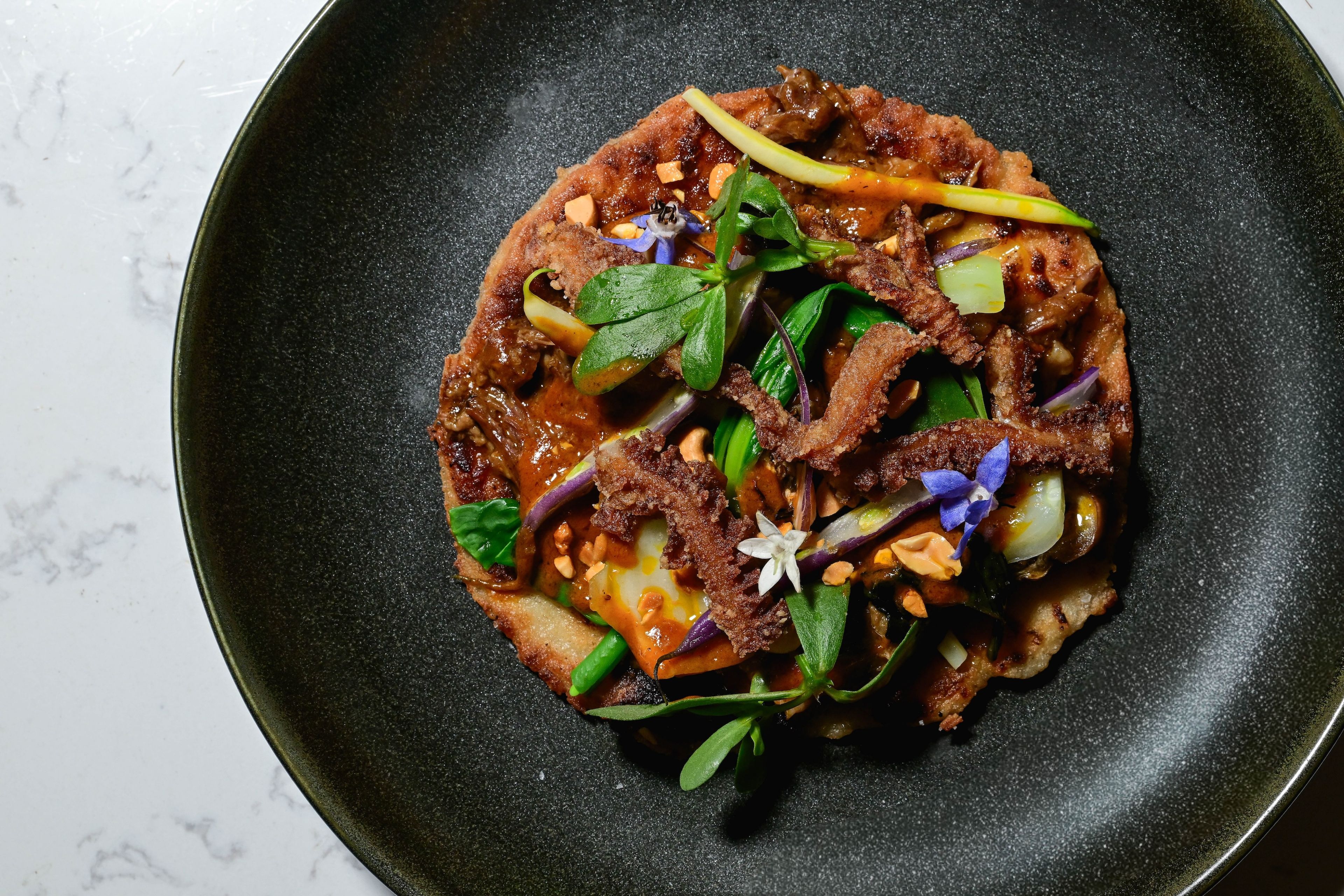 Magbitang's take on kare-kare: oxtail and tripe on a savory rice crêpe. (Photo: Max Flatow)