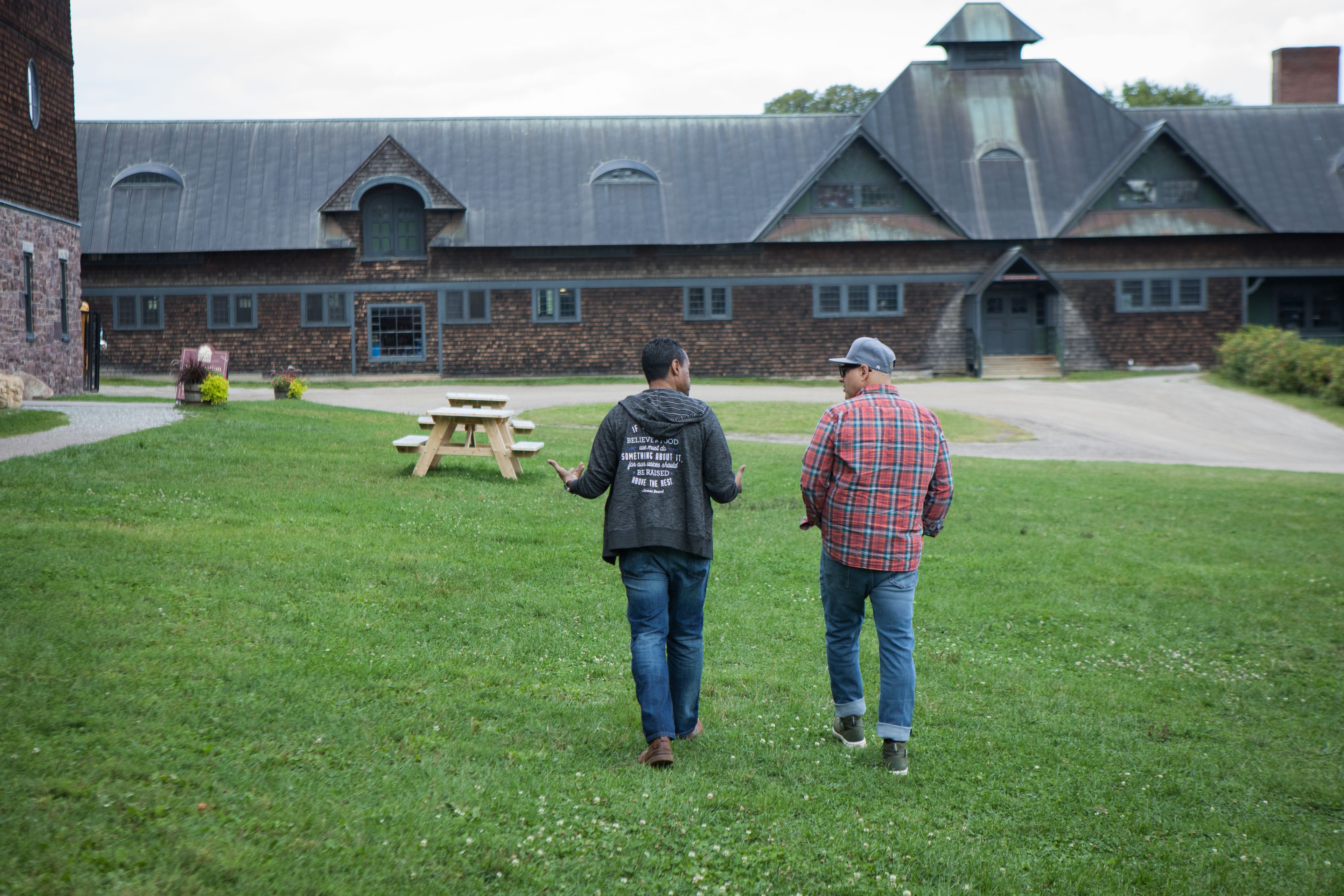 Two chefs walking away from camera towards a farm building