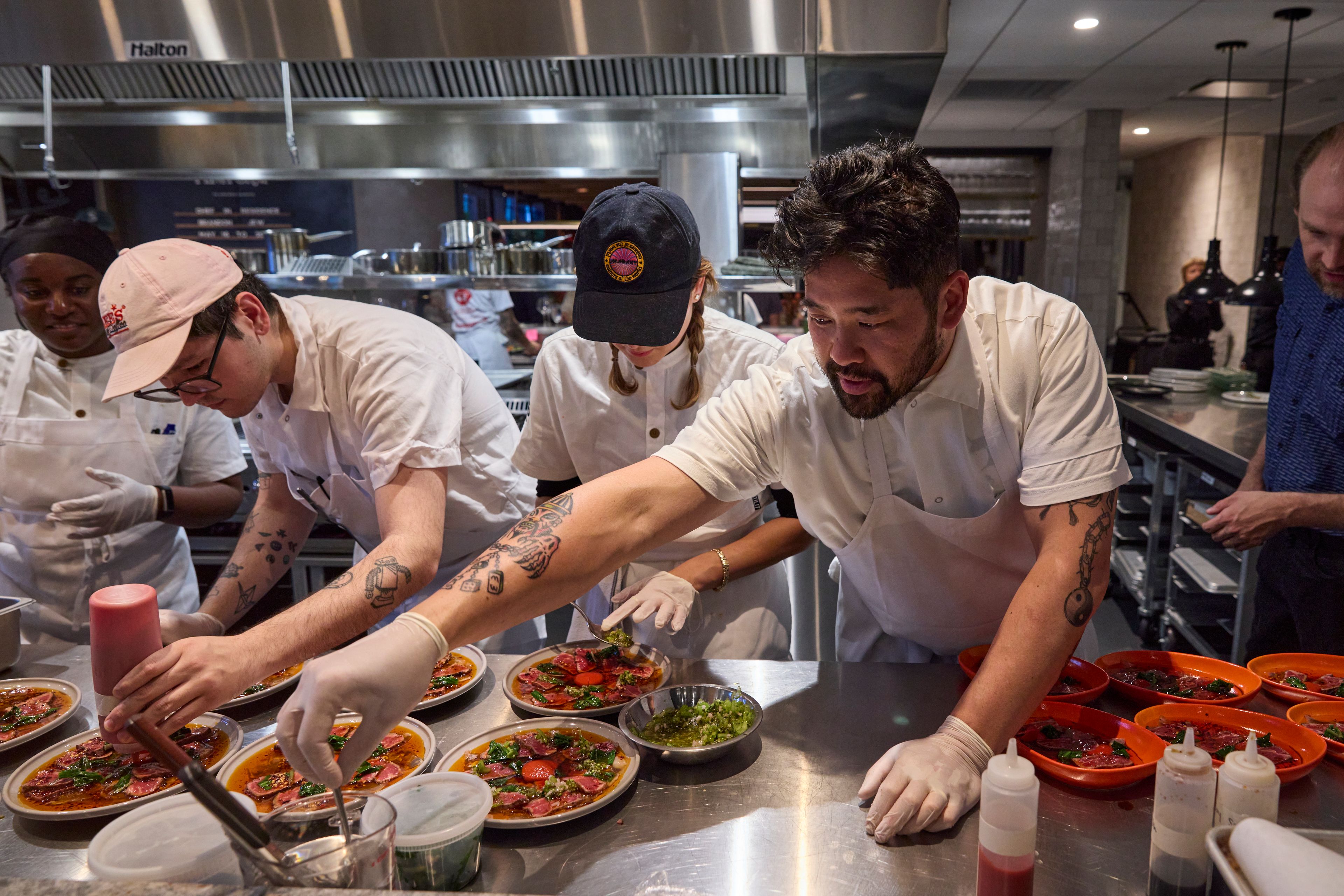 Chefs reaching over a counter plating