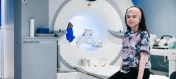 Girl sitting on MRI scanner