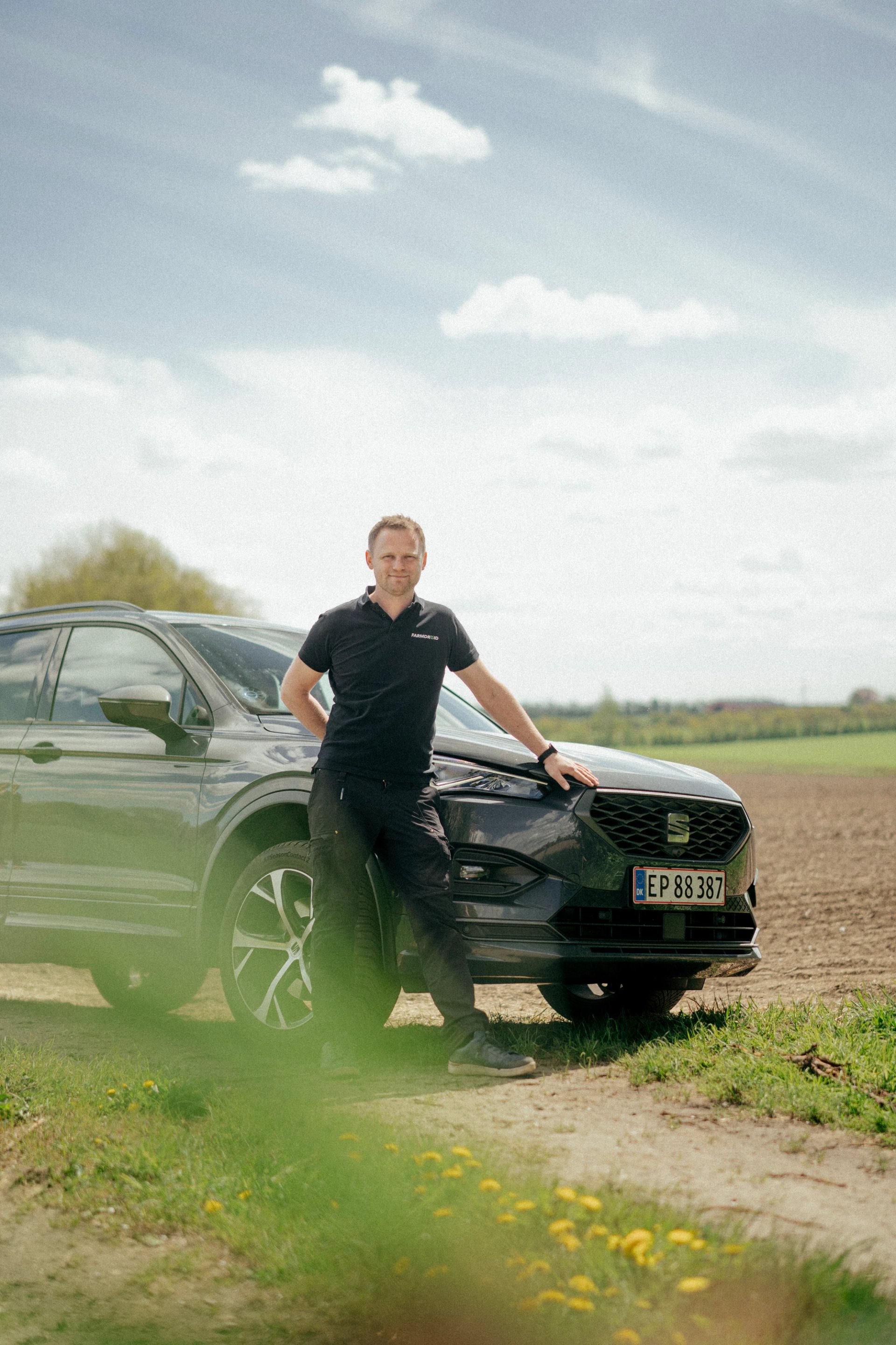 FarmDroid-medarbejder ved firmabil i landlige omgivelser.