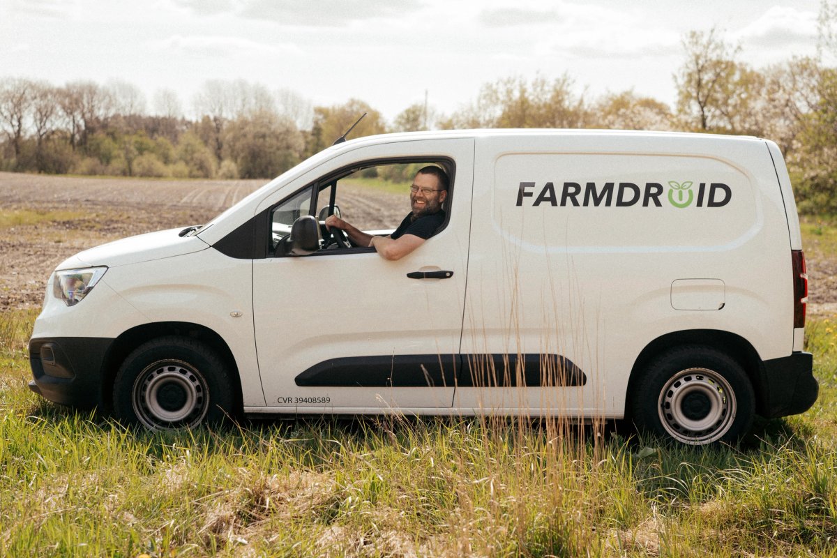 Medarbejder fra FarmDroid kører servicebil på markvej ved landbrugsområde.
