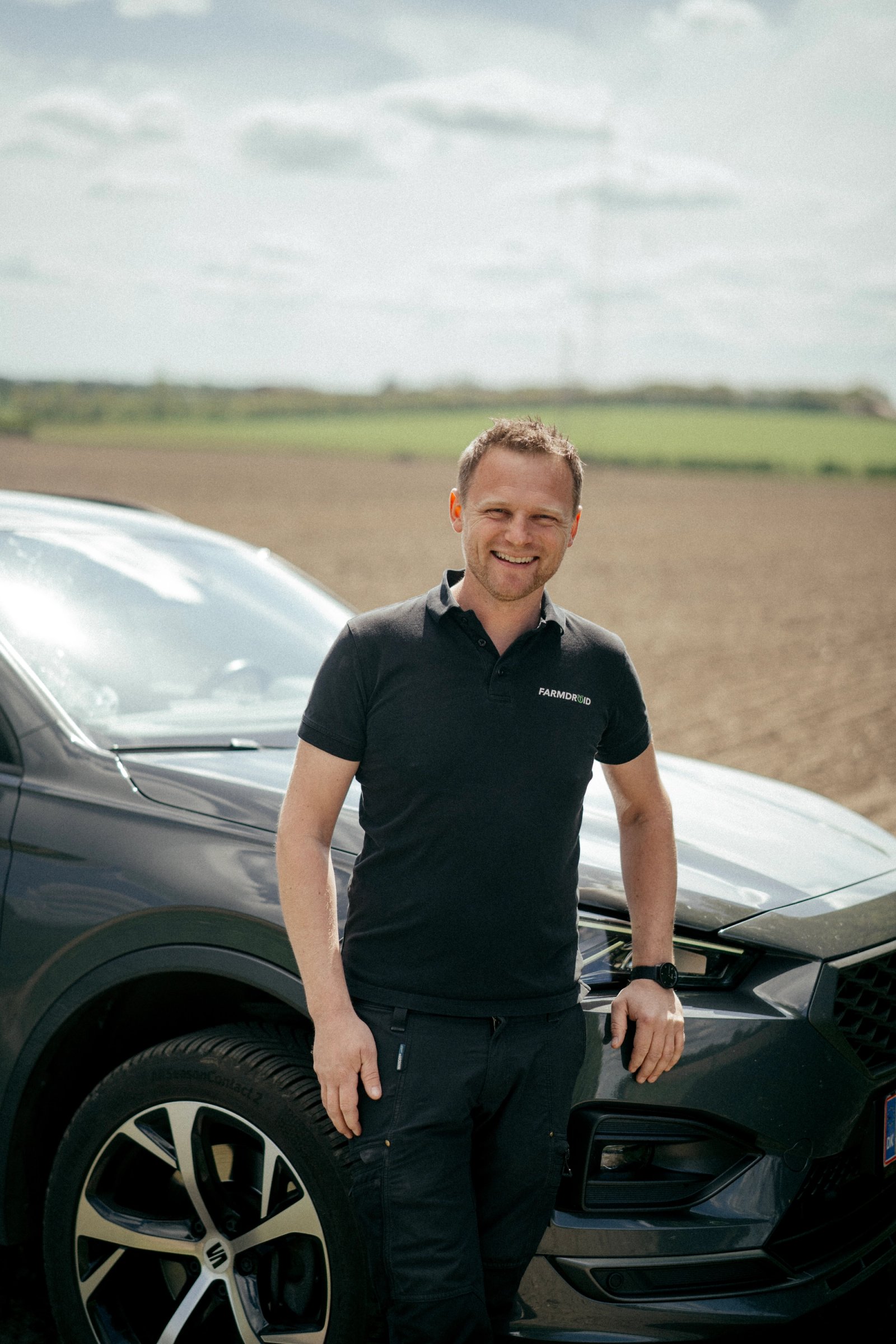 FarmDroid medarbejder står foran firmabil på landet
