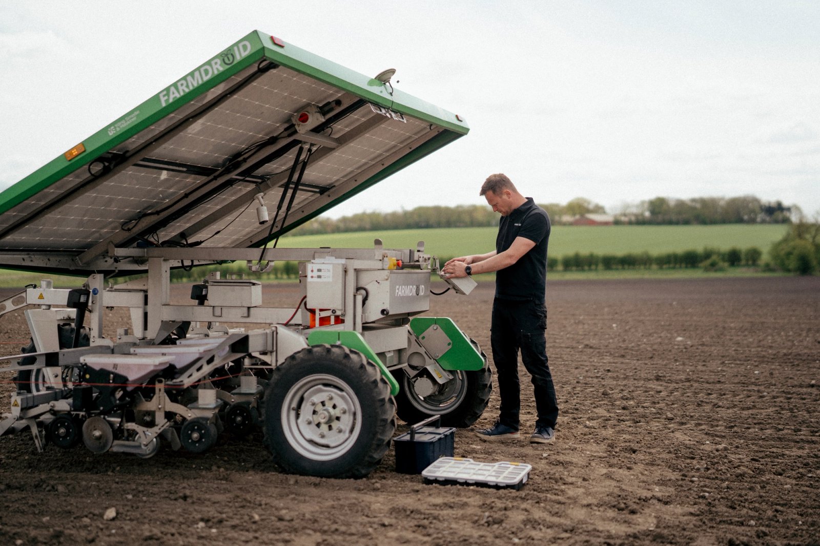 FarmDroid-medarbejder arbejder med automatiseret landbrugsmaskine på mark.