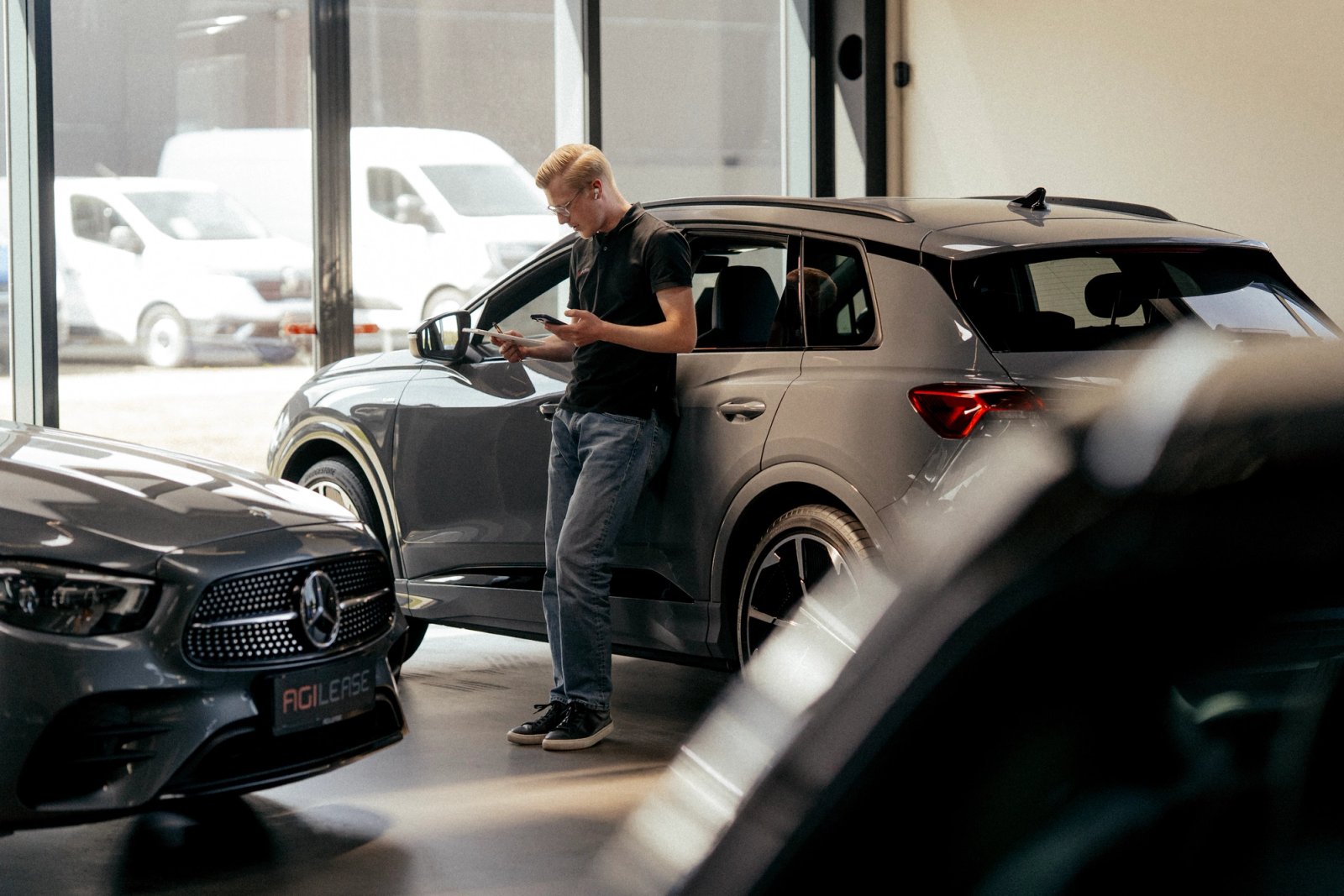 Leasingrådgiver i Agileases showroom blandt firmabiler og leasingbiler.