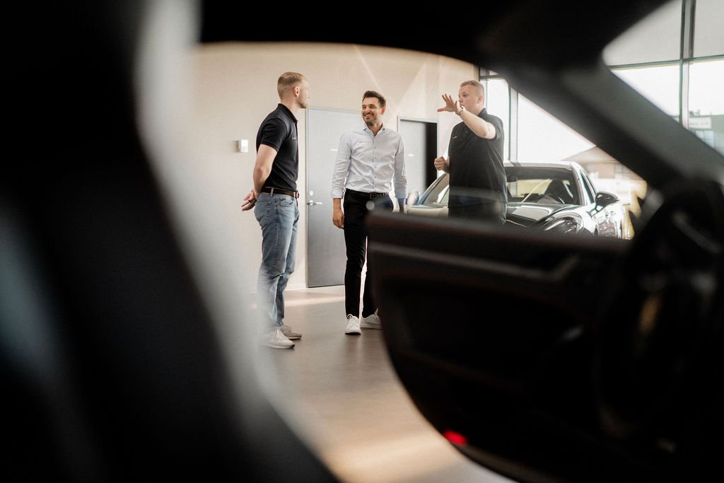Leasingrådgivere taler sammen i Agileases showroom blandt leasingbiler og firmabiler.