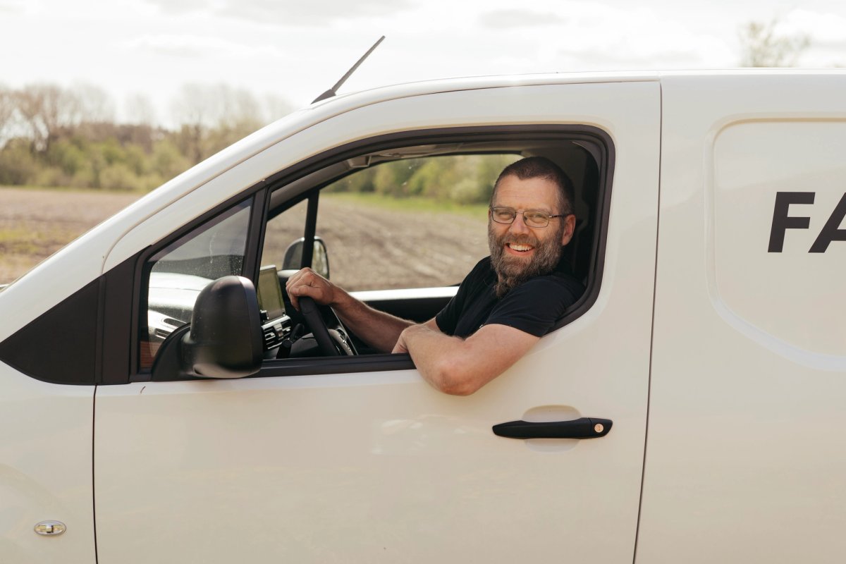Medarbejder fra FarmDroid kører servicebil på markvej ved landbrugsområde.