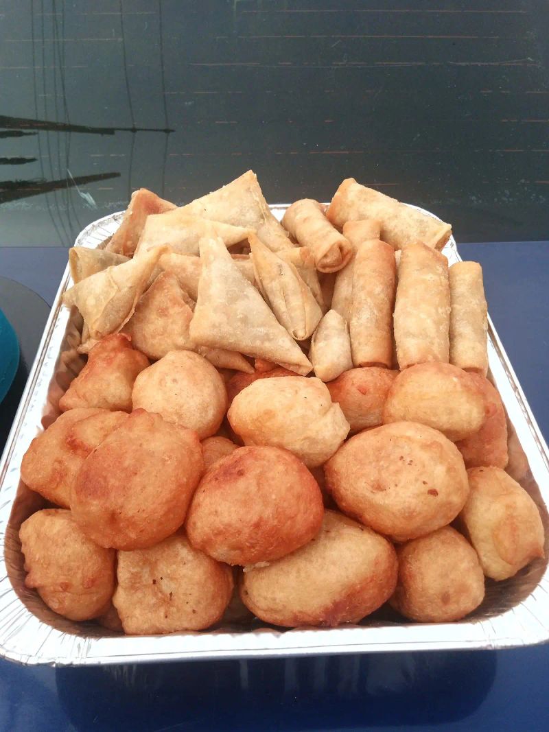 A tray of small chops, including samosas and fried dough balls
