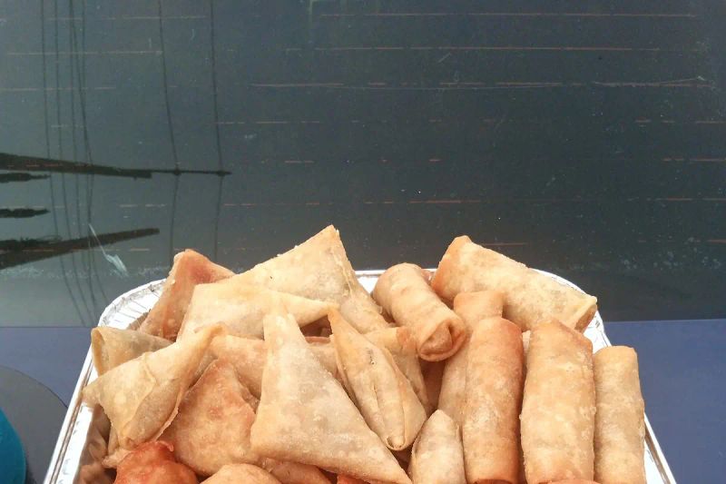 A tray of small chops, including samosas and fried dough balls