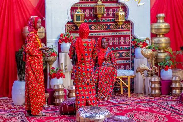 A ceremony stage set with red drapes, patterned fabric and brass vessels