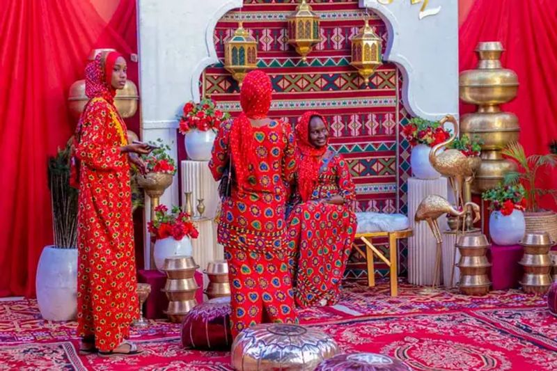 A ceremony stage set with red drapes, patterned fabric and brass vessels