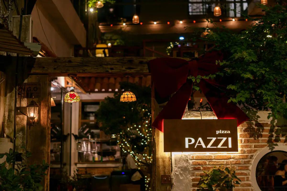 Nhà hàng pizza Pazzi với biển hiệu sáng, đèn trang trí Tiffany, cổng vào trang nhã ban đêm, phong cách ẩm thực Ý cổ điển