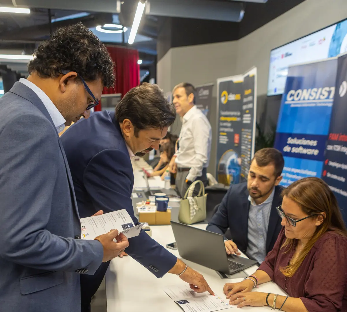 Álvaro Cruz and Belén González staff the Hard2bit stand while Adrián González and Thilina Manana review a leaflet