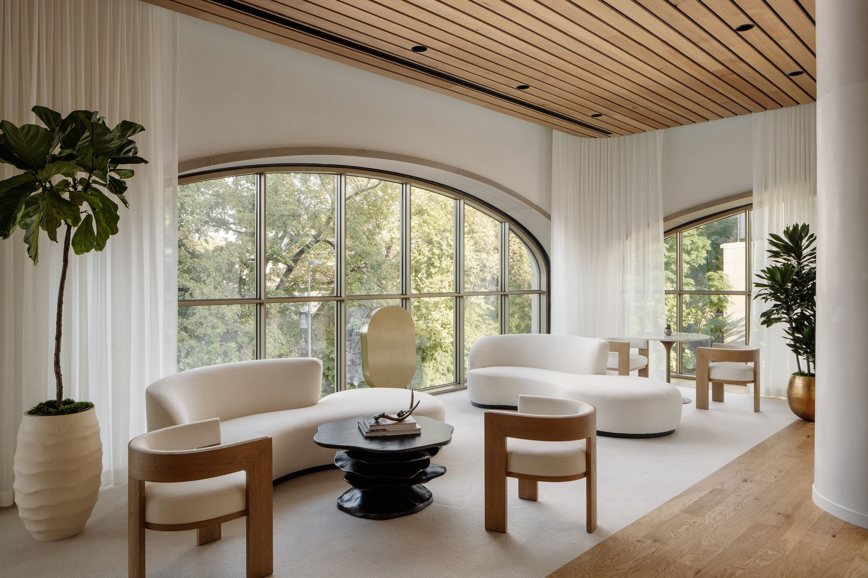 Lounge of curved white sofas facing a tall arched window