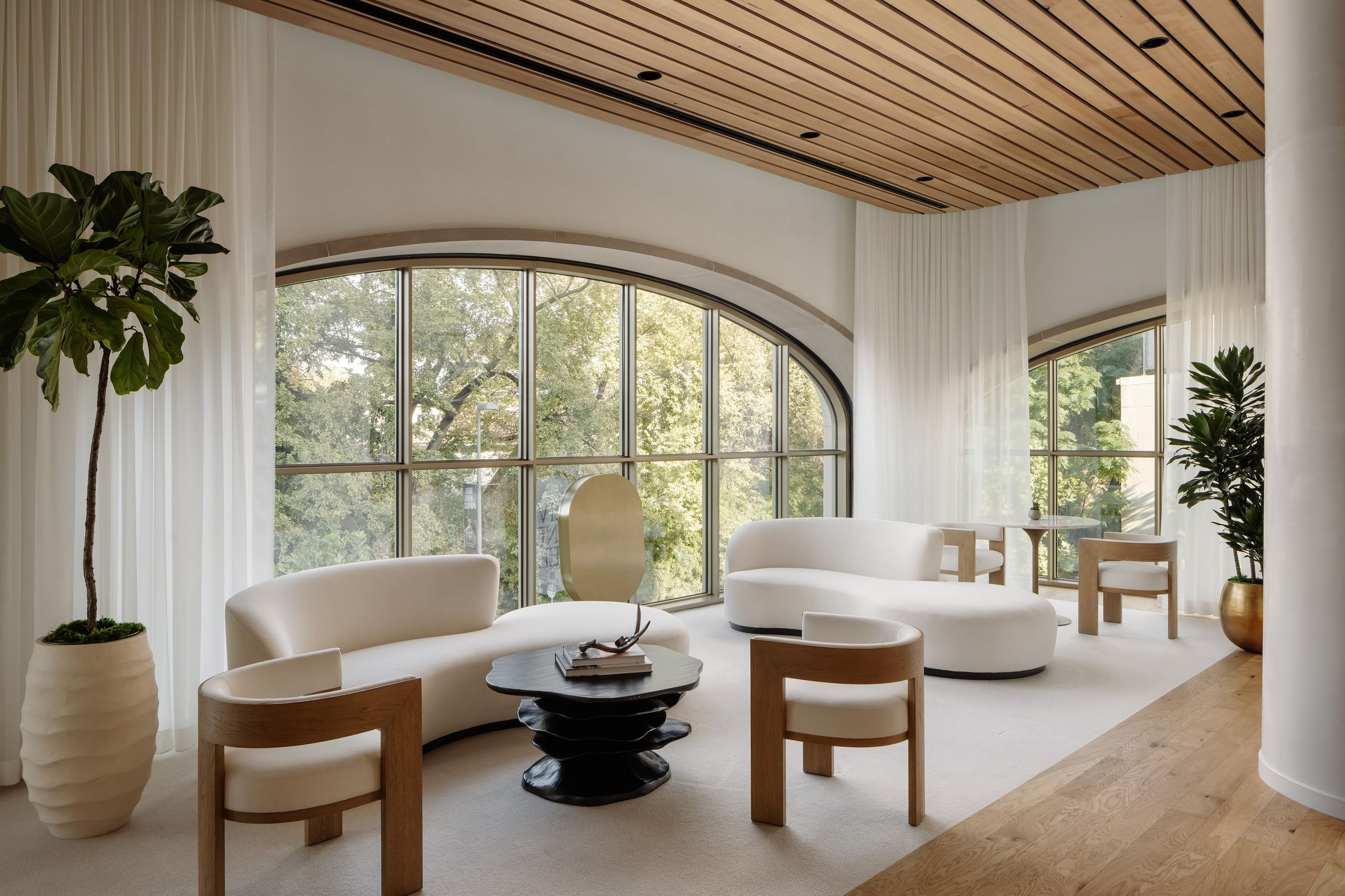Lounge of curved white sofas facing a tall arched window