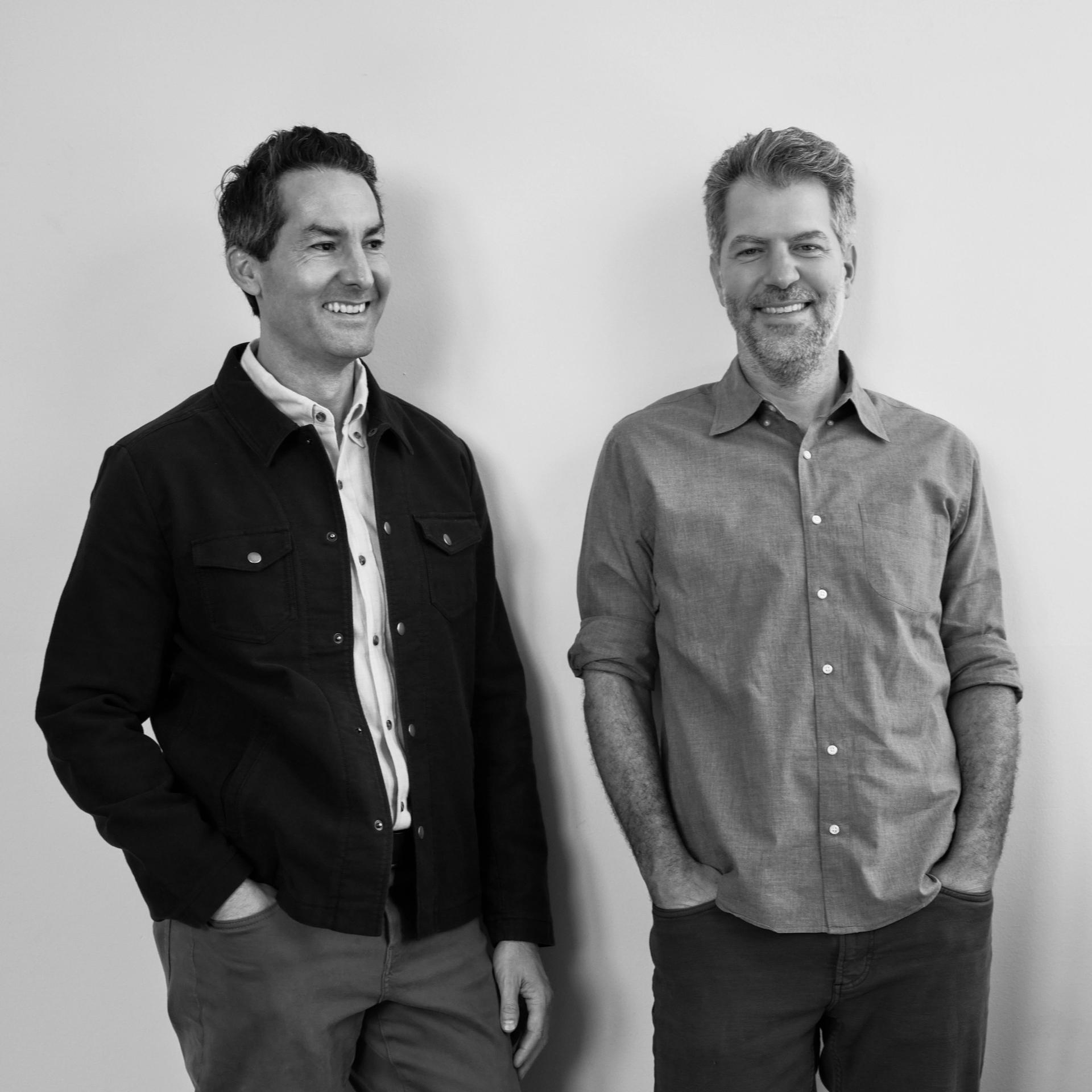 Joel Nolan and Andrew Bell, co-founders of Nolan Bell, standing against a white wall.