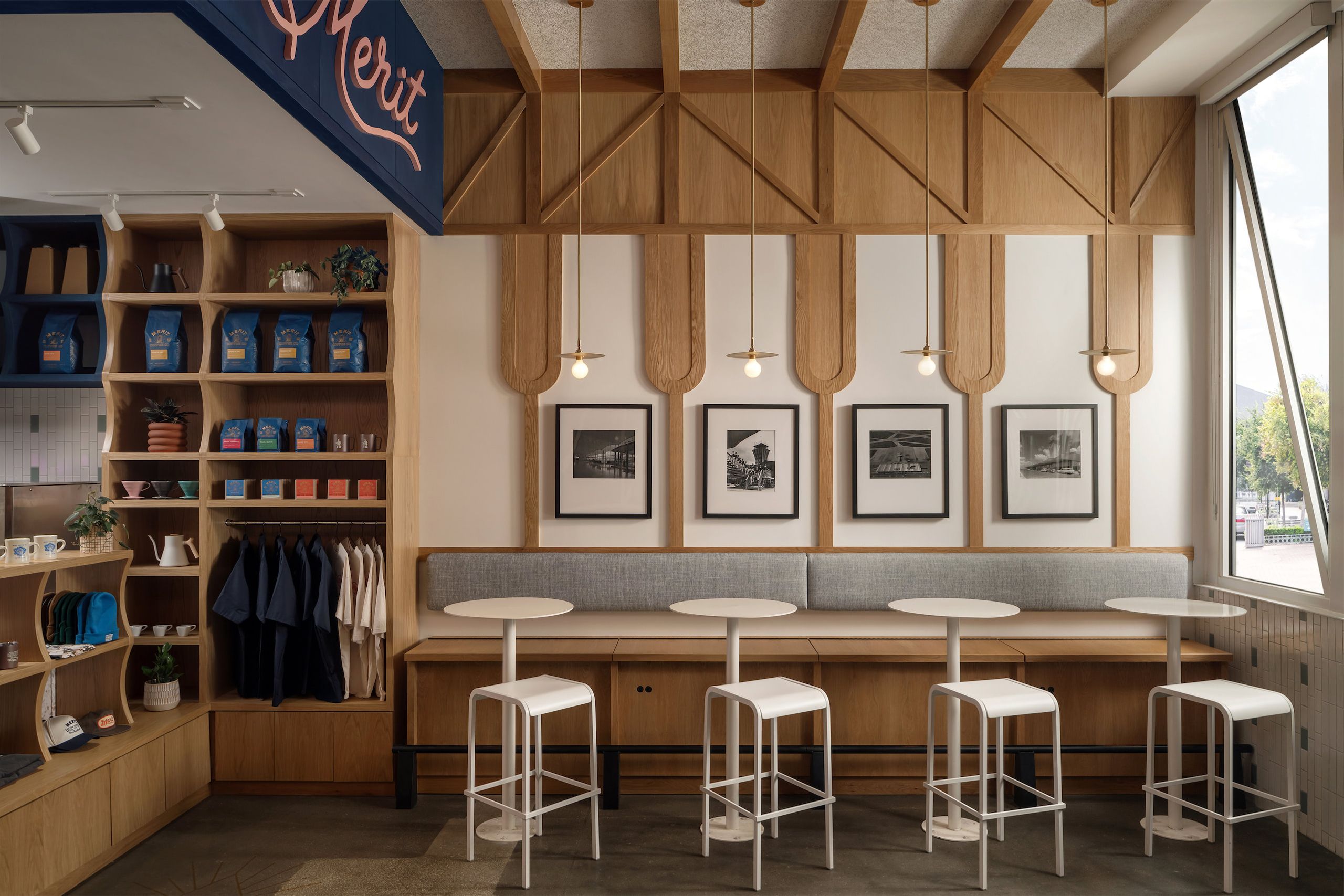 Cafe interior with wood shelving, a long banquette, and round tables