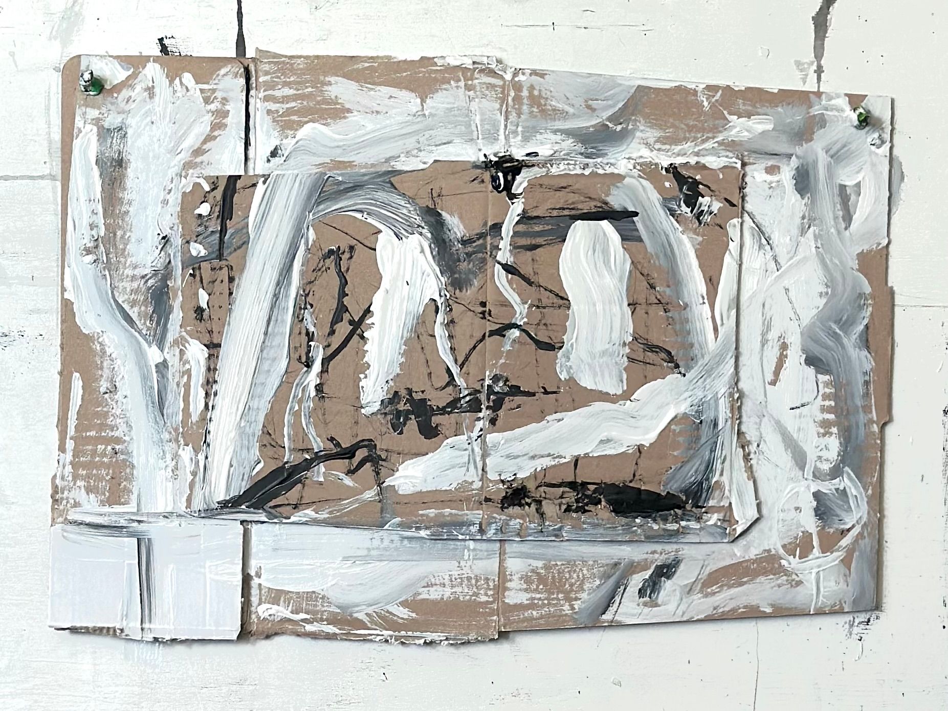 Abstrakt komposisjon på tre lag av bølgepapp. Figurlignende strøk og  linjer i hvitt rundt et midtparti med relativt tynne sorte linjer. 