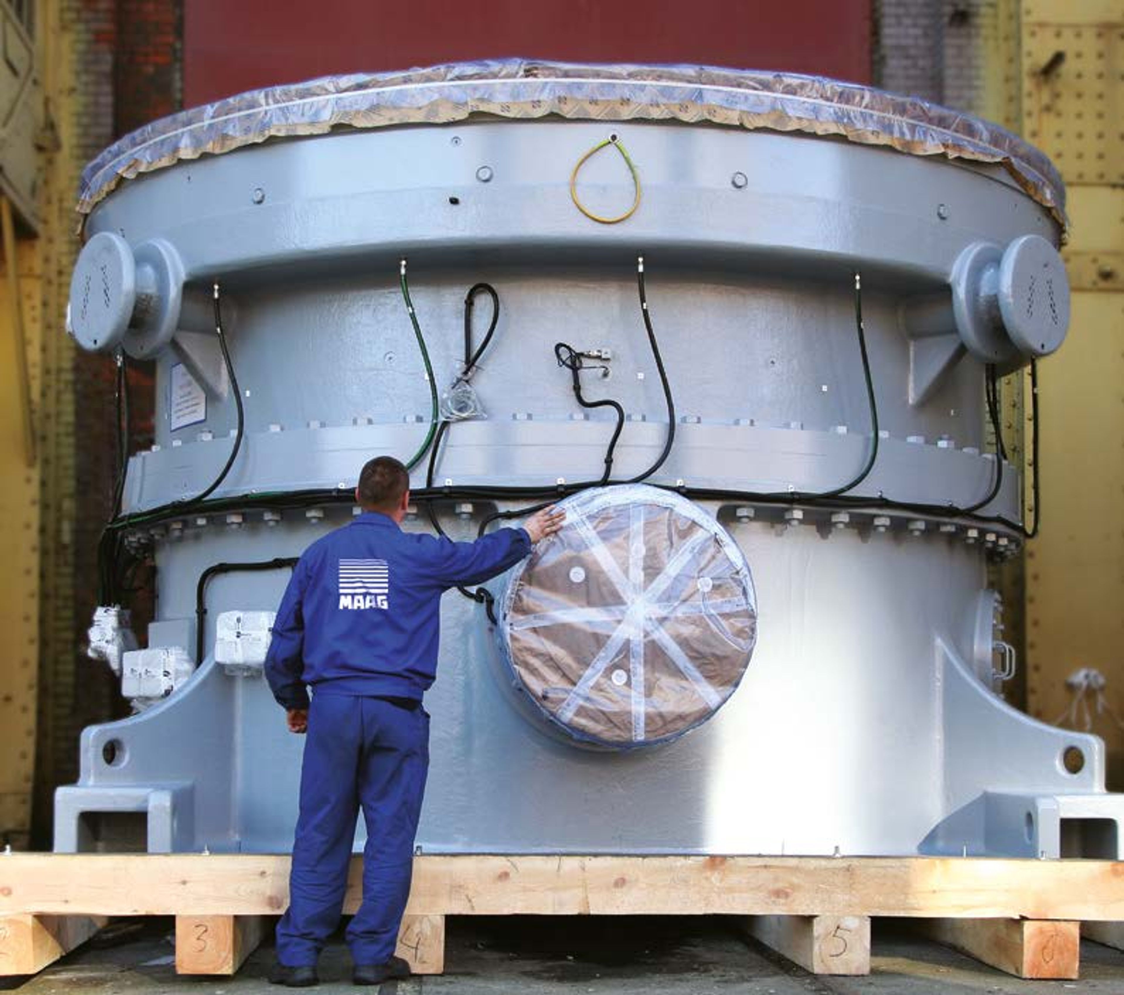 Man standing before large vertical roller mills