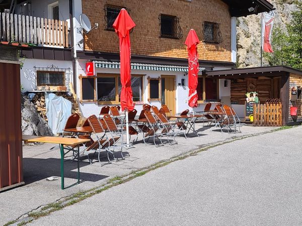 Frontansicht des Gaichtpassstüberl mit Holzfassade und Schild, Terrasse mit roten Schirmen
