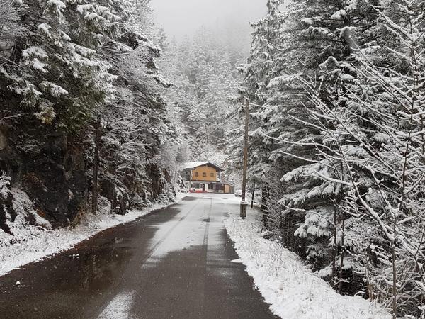 Verschneite Straße zwischen Tannen, Gaichtpassstüberl am Ende des Weges