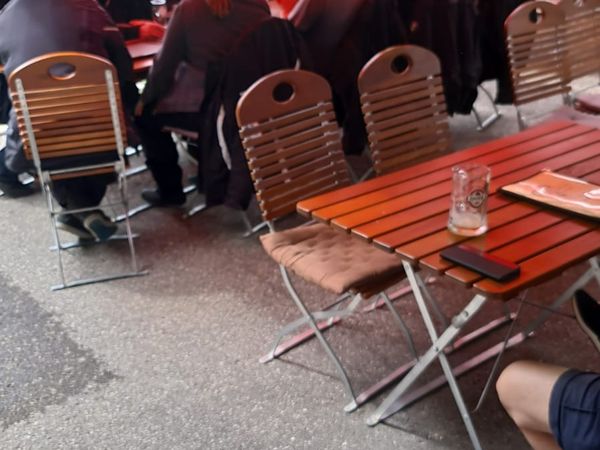 Volle Terrasse mit Gästen unter roten Almdudler-Schirmen, Motorräder sichtbar