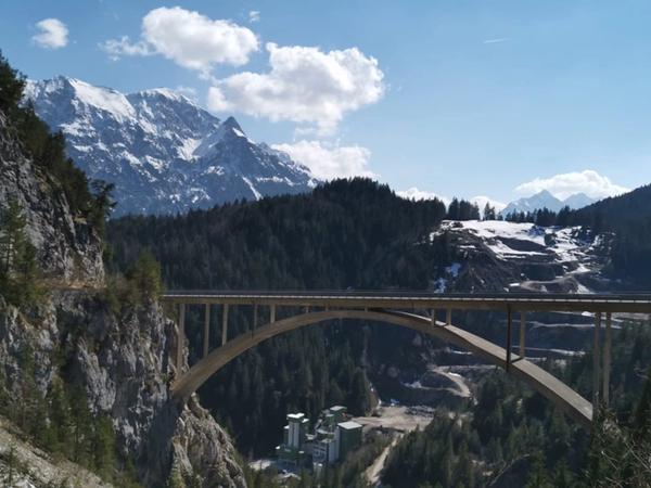 Weitwinkelblick auf die Gamstalbrücke mit Schneegipfeln und blauem Himmel