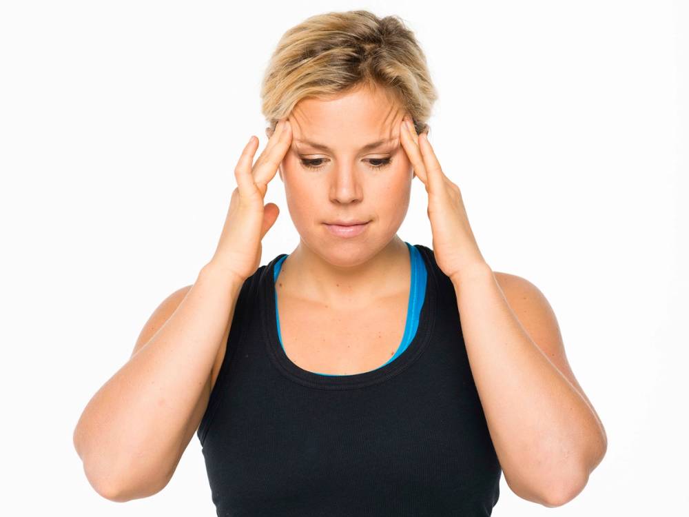 En person med blondt hår som holder hendene opp til hodet, klar for massasje, mot en hvit bakgrunn.