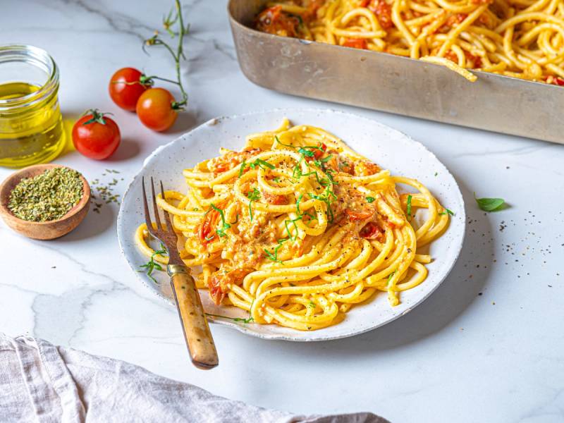Spagetti med baked feta ost og tomater på en hvit tallerken