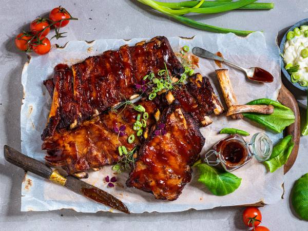 Marinert og grillet ribbe med grønnsaker og saus på et fat, klar til servering.