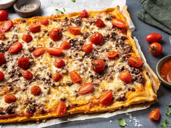 En pizza med kjøttdeig, cherrytomater og ost på en stekeplate