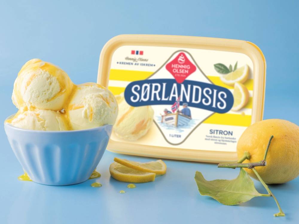Hemmelig is med sitronsmak i en blå bolle, med sitron og sitrusskiver ved siden av, og en pakke med Sørlandis sitronis i bakgrunnen.