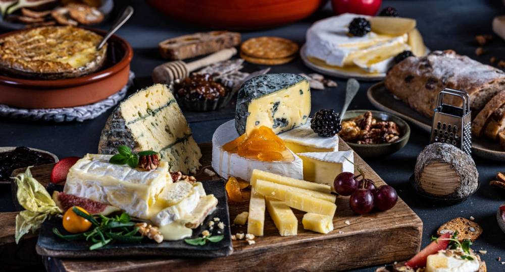 Et utvalg av ulike oster, frukt og kjeks på et bord, klar for helgekos.