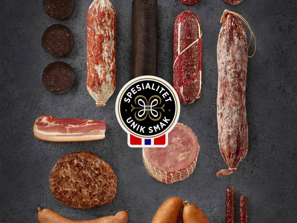 Ulike typer av kjøtt og pølser på en stekeplate, med en logo som sier spesialitet og unik smak.