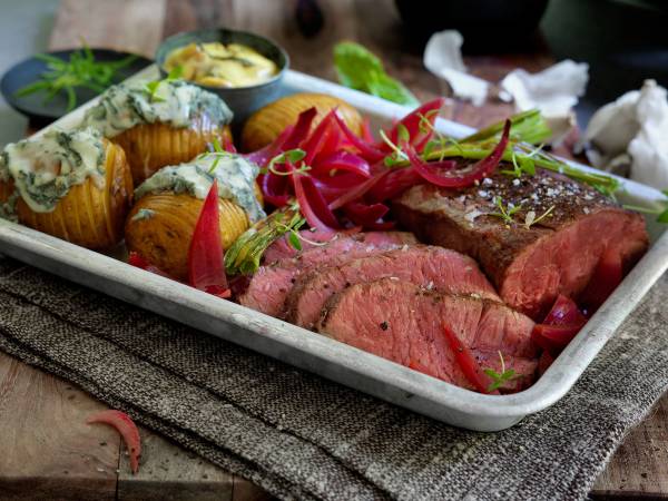 Stekt biff med ovnsbakte poteter og grønnsaker på et serveringsfat.