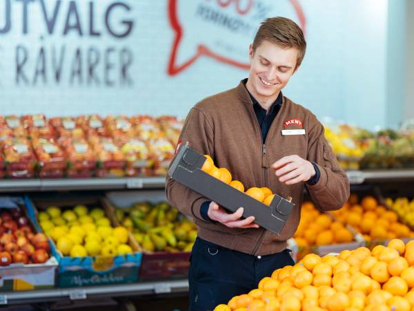 En matarbeider fyller på varer i frukt- og grøntavdelingen.