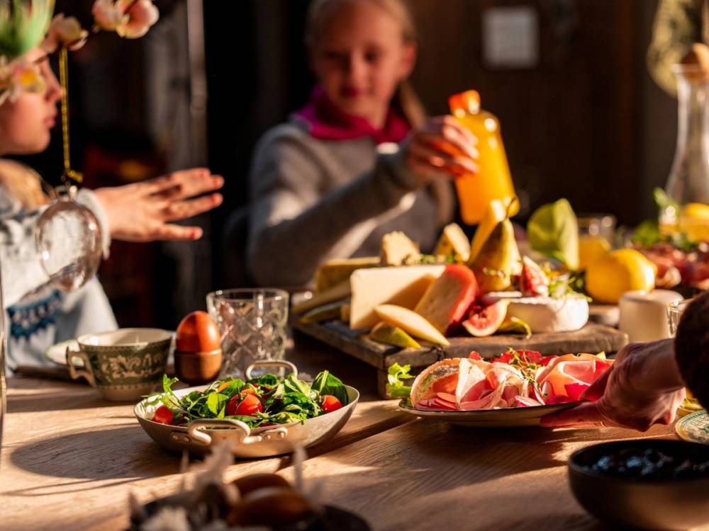 To personer som spiser og deler mat på et bord med ulike retter og drikke, i et innendørs miljø.