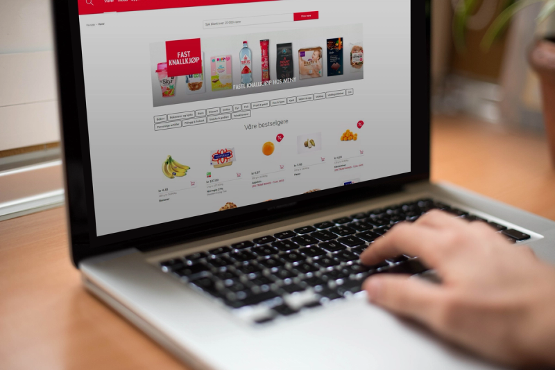 Nærbilde av en person som handler i en nettbutikk på en bærbar datamaskin, med produktbilder og bestillingsknapper på skjermen.