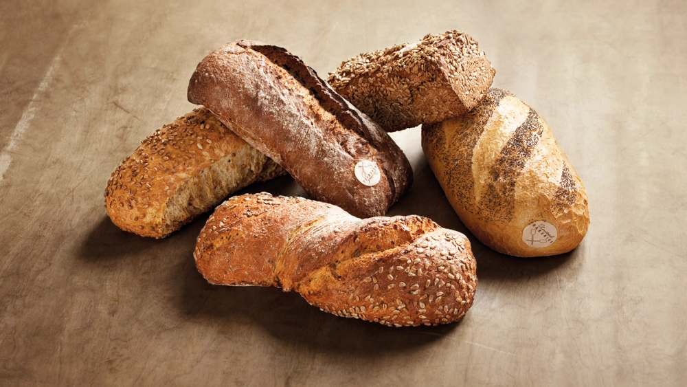 Ulike typer brød og kaker ligger på et bord.