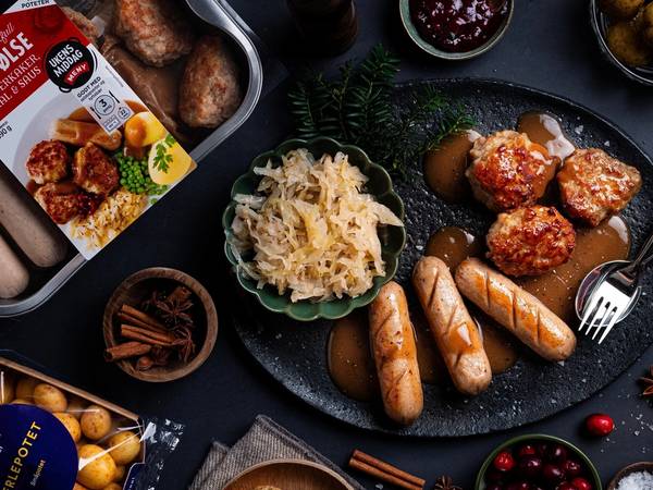 Julepølse med potetsalat og julemat på et dekket bord