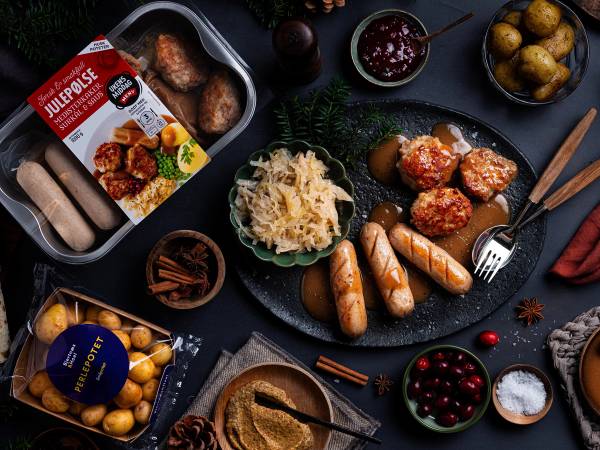 Julepølse med potetsalat og julemat på et dekket bord