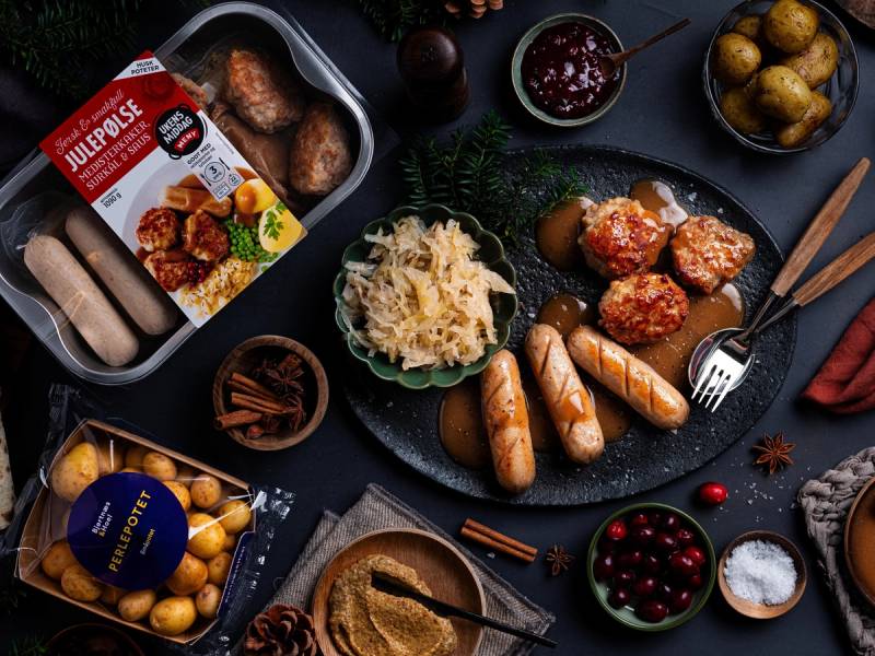 Julepølse med potetsalat og julemat på et dekket bord