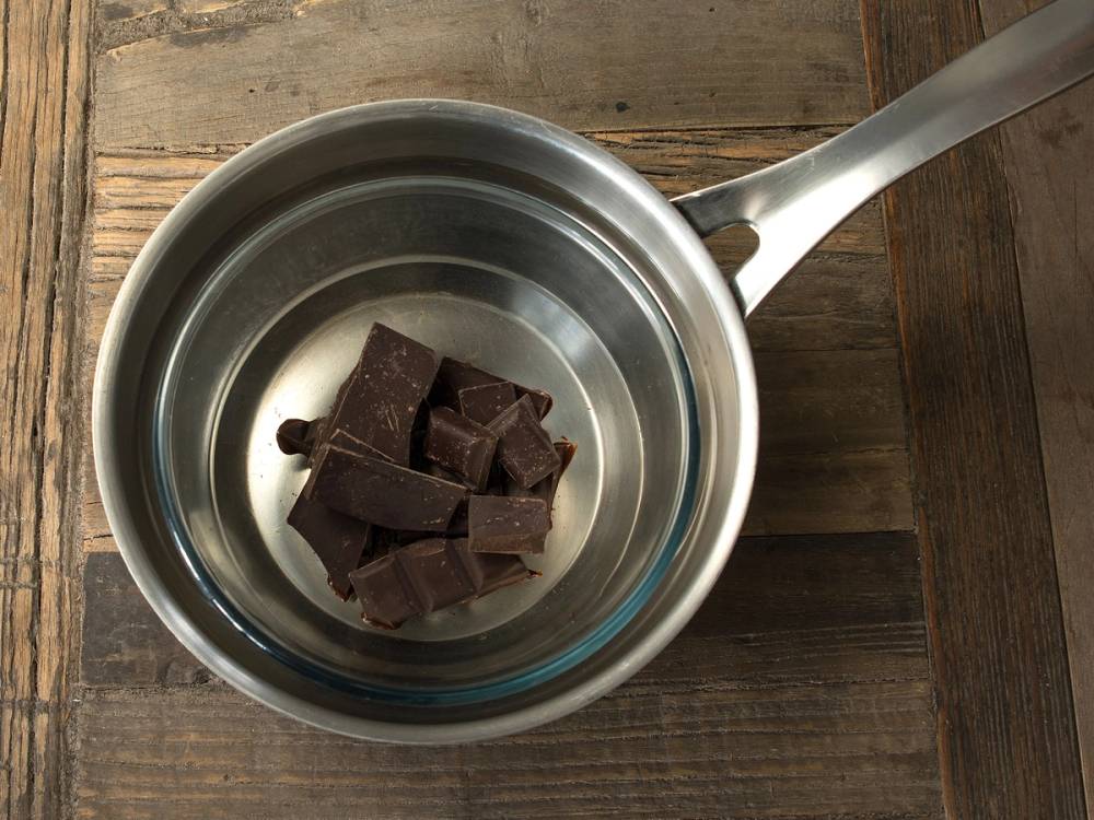 Smeltet sjokolade i en liten kjele på et trebord
