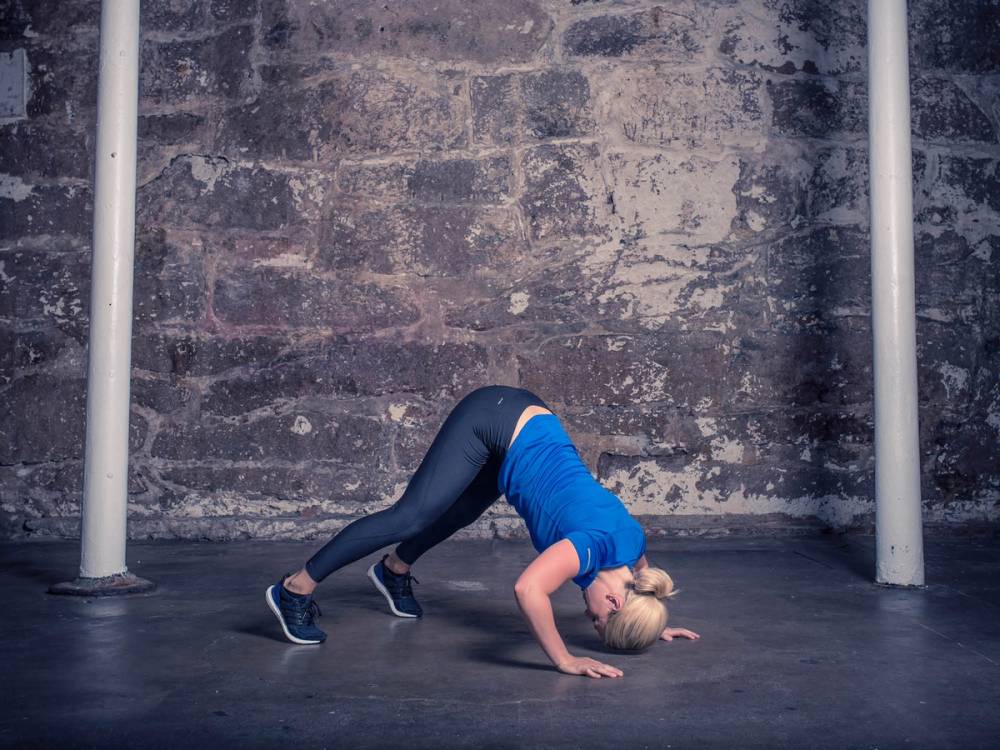 En person utfører en opp-ned skulderpress med vekter i et treningsrom.