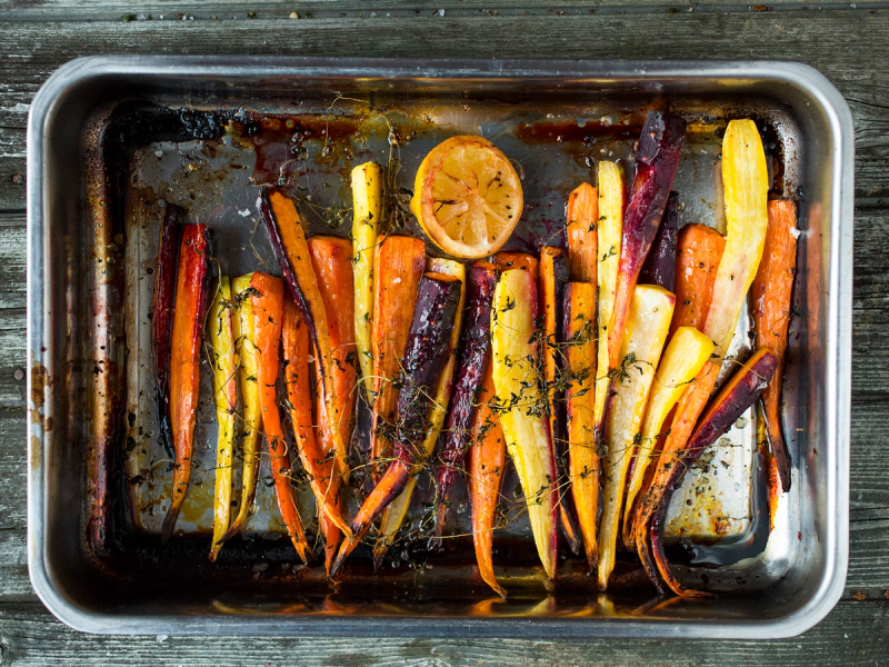 Fargerike regnbuegulrøtter på en stekeplate med sitronbiter, klar for baking eller steking.